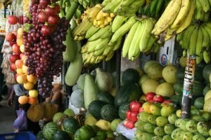 Vibrant arrangement of fresh tropical fruits at a local market, showcasing bananas, melons, and more.
