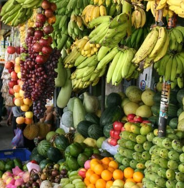 Vibrant arrangement of fresh tropical fruits at a local market, showcasing bananas, melons, and more.